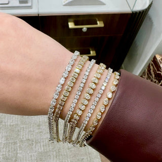 About: This round tennis bracelet features a continuous row of bezel set diamonds framed in 14K gold for a smooth, streamlined finish. Clean and versatile, it offers an easy take on classic styling.

Diamond Details: Approx 46 Emerald Cut Lab Grown Diamonds

Total Carat Weight:&nbsp;Approx 7 Carats (Each 0.15 Carats)
Color: E/F
Clarity:&nbsp;VS

Metal:&nbsp;14K Yellow Gold

Width:&nbsp;Approx 5.5 mm

Length: Available in 6.5" or 7"

Closure:&nbsp;Under Locking Clasp