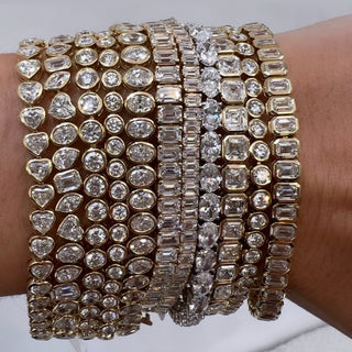 About: This round tennis bracelet features a continuous row of bezel set diamonds framed in 14K gold for a smooth, streamlined finish. Clean and versatile, it offers an easy take on classic styling.

Diamond Details: Approx 46 Emerald Cut Lab Grown Diamonds

Total Carat Weight:&nbsp;Approx 7 Carats (Each 0.15 Carats)
Color: E/F
Clarity:&nbsp;VS

Metal:&nbsp;14K Yellow Gold

Width:&nbsp;Approx 5.5 mm

Length: Available in 6.5" or 7"

Closure:&nbsp;Under Locking Clasp